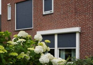 Buitenzonwering met ritsscreens gemonteerd op een modern bakstenen huis