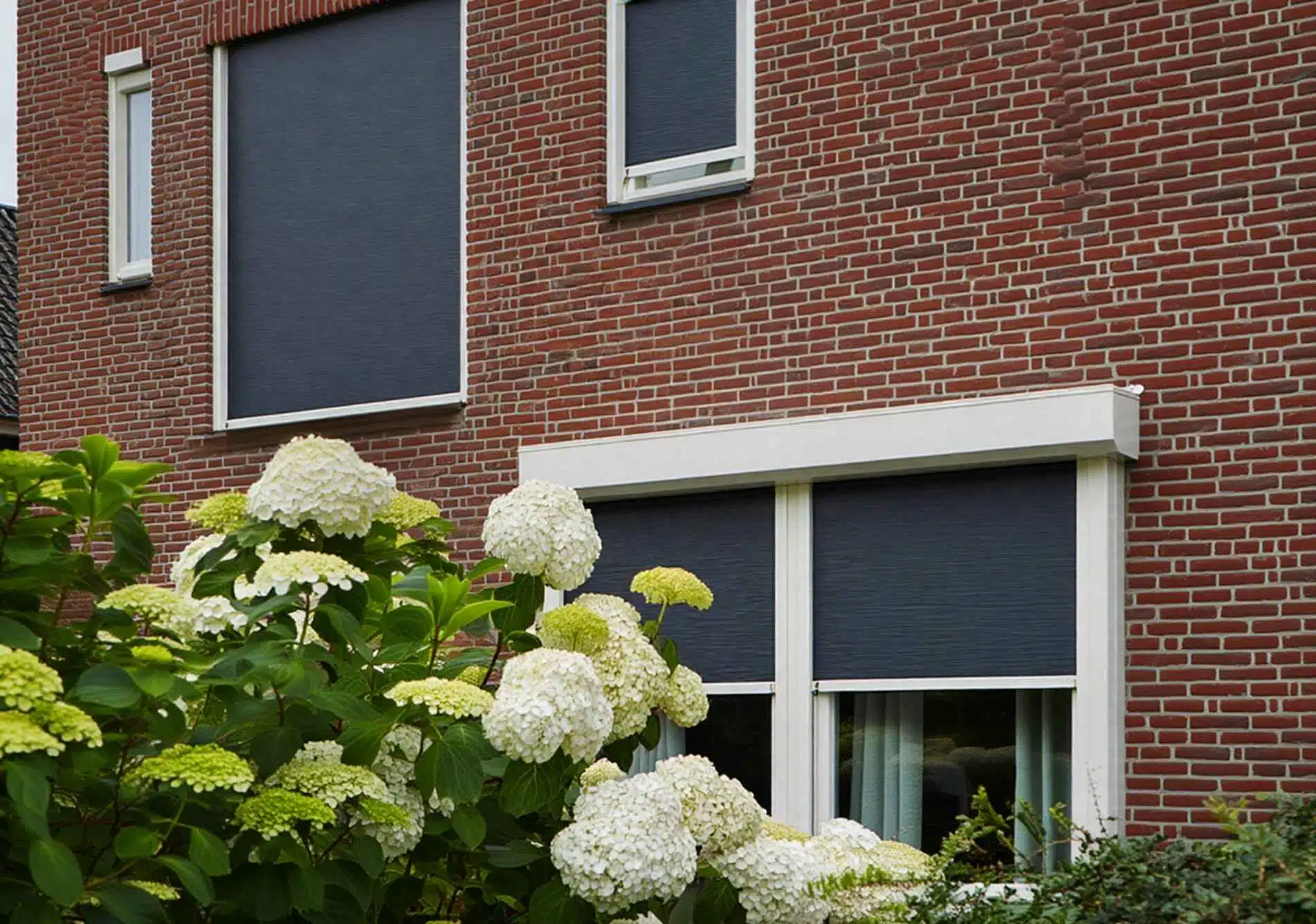 Buitenzonwering met ritsscreens gemonteerd op een modern bakstenen huis