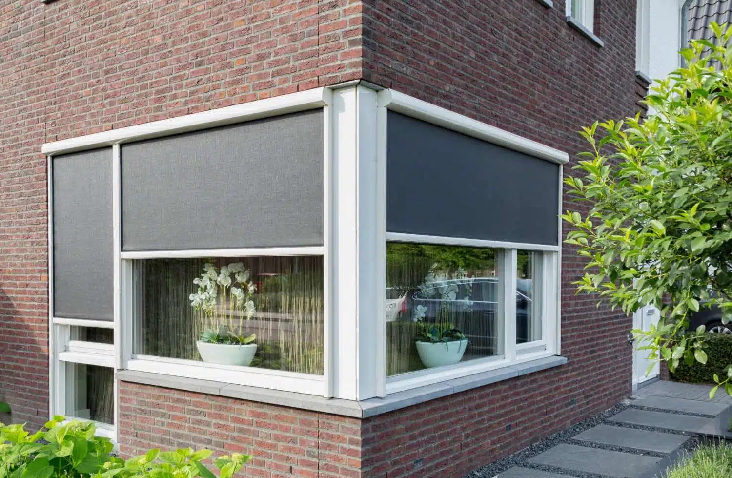 Ritsscreens op een hoekwoning als zonwering tegen de zomerhitte