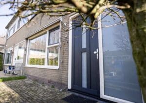 Antracietkleurige kunststof voordeur met zijlicht in bakstenen gevel, geplaatst door Markant Kozijnen Oosterwolde.